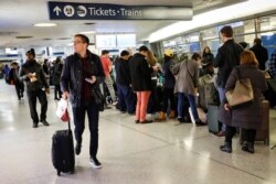 FILE - Travelers wait in the boarding area for trains during the Thanksgiving holiday travel rush at Pennsylvania Station in New York, Nov. 27, 2019.