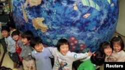 Niños japoneses sostienen un "planeta feliz" hecho de Shibori-zome, un método tradicional japones.