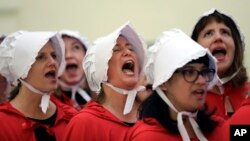 FILE - Activists dressed as characters from "The Handmaid's Tale" chant in the Texas Capitol Rotunda as they protest SB8, a bill that would require health care facilities to bury or cremate any fetal remains, whether from abortion, miscarriage or stillbirth.