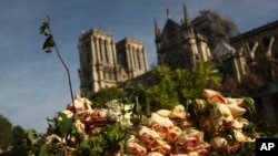 Un ramo de flores junto al río Sena cerca de la catedral de Notre Dame (al fondo), en París el jueves, 18 de abril de 2019. 