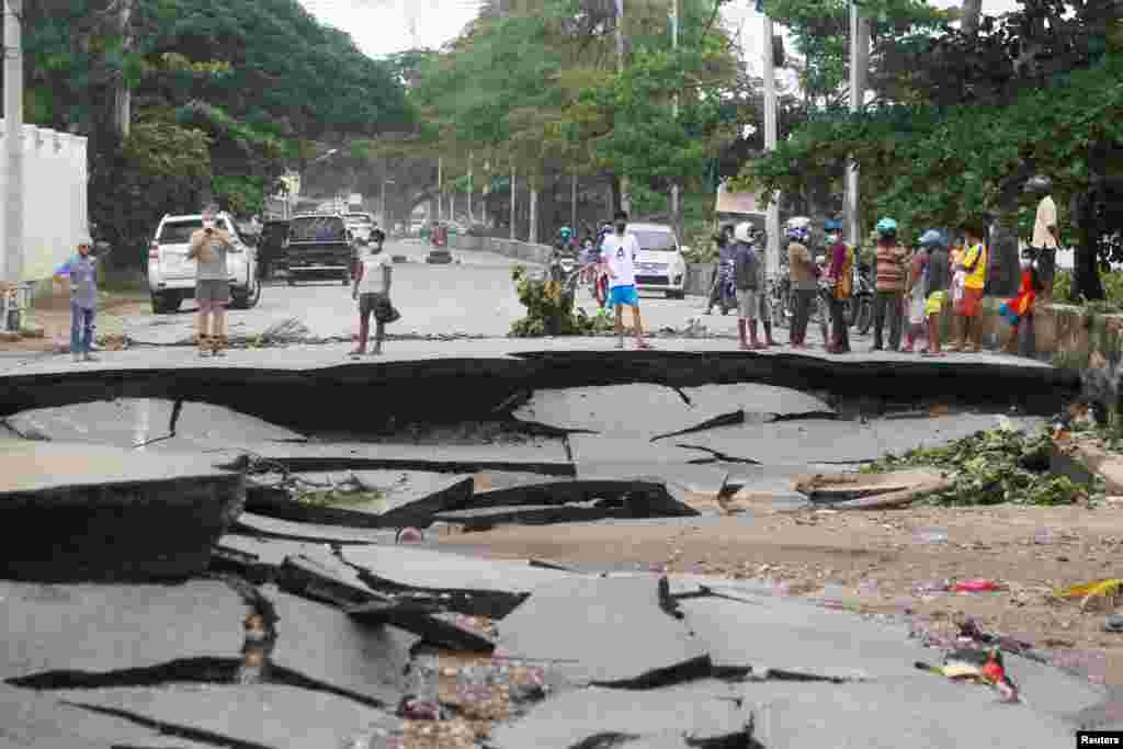 People stand near roads damaged by floods after heavy rainfall in Dili, East Timor.