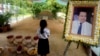 In this Nov. 20, 2016 photo, a girl stands by a portrait of Kem Ley, a Cambodian prominent political analyst, at his grave in Ang Takok, Cambodia. Kem Ley, a poor rice farmer's son turned champion of Cambodia's have-nots, was sipping his usual iced latte in the same chair he had occupied most mornings for years when a former solider he may never have met walked into the Caltex gas station cafe. Armed with a semi-automatic Glock pistol, the assassin fired into his chest and head, execution-style. Then he walked casually away from the scene. (AP Photo/Denis Gray)