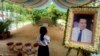 In this Nov. 20, 2016 photo, a girl stands by a portrait of Kem Ley, a Cambodian prominent political analyst, at his grave in Ang Takok, Cambodia. (AP Photo/Denis Gray)