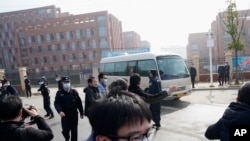 Journalists and security personnel gather near the entrance of the Wuhan Institute of Virology after a visit by the World Health Organization team in Wuhan in China's Hubei province on Wednesday, Feb. 3, 2021. (AP Photo/Ng Han Guan)