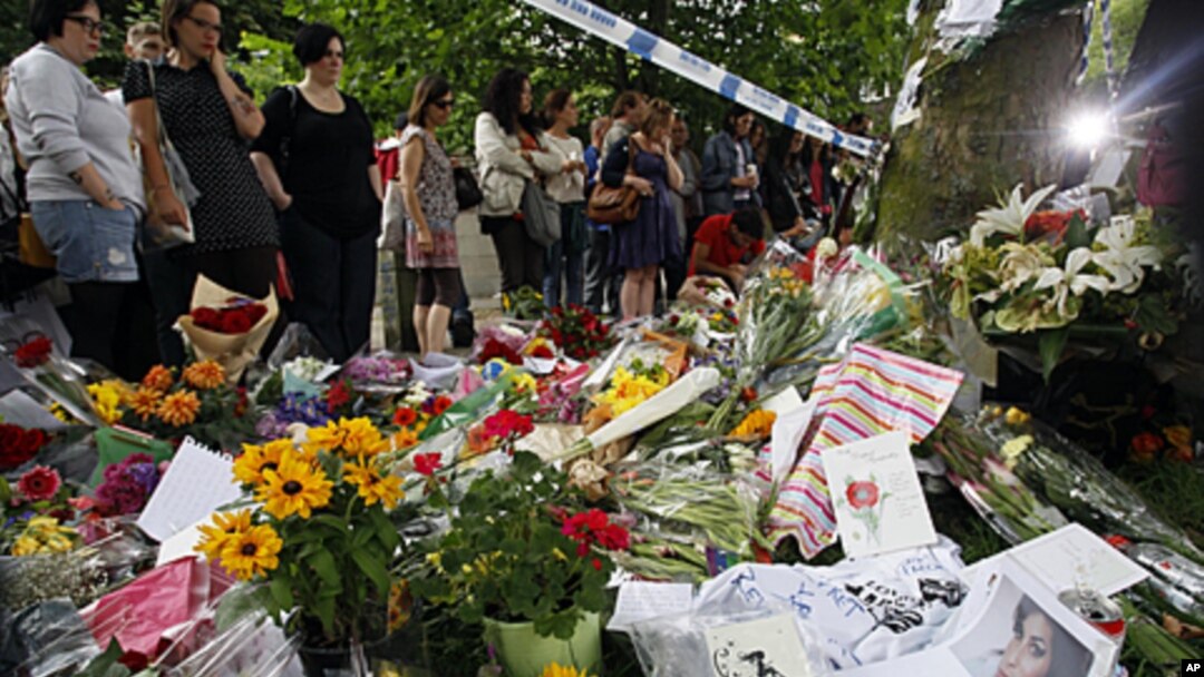 Fans gather around flowers and tributes near the home of British singer Amy Winehouse in London, July 25, 2011