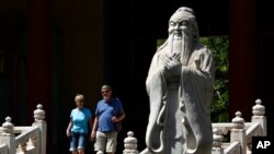 FILE - Tourists walk past a statue of philosopher Confucius in Beijing, May 28, 2019. At that time, China used five-day Confucian culture immersion courses for religious leaders as part of a campaign to extend government control over faith communities.