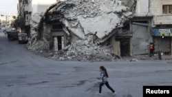 Une fille court devant un immeuble endommagé par des bombardements dans la région de Maaret al-Numan sous contrôle de la rébellion, dans la province d'Idlib, Syrie, 21 décembre 2015.