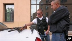 Les policiers de l'Université du Nouveau-Mexique Robert Rush (g) et Ernesto Pacheco regardent les armes trouvées au domicile de l'étudiant Kevin Boyar mardi 6 mai 2008 à Albuquerque. K. Boyar a été arrêté pour avoir transporté illégalement des armes sur le campus.