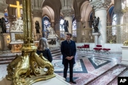 Presiden Prancis Emmanuel Macron berbincang dengan seorang pekerja seni saat meninjau interior katedral Notre-Dame de Paris di Paris yang telah dipugar, Jumat, 29 November 2024. (Christophe Petit Tesson/Pool via AP)