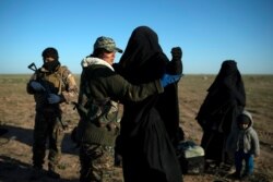 FILE - A woman is frisked by a U.S.-backed Syrian Democratic Forces (SDF) fighter at a screening area after being evacuated out of territory held by Islamic State group militants, in the desert outside Baghuz, Syria, March 1, 2019.