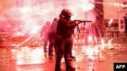 Fireworks shot by protesters explode near police in riot gear firing tear gas during a nationwide protests against the Georgian government's decision to shelve EU membership talks, in Tbilisi, Dec. 2, 2024.