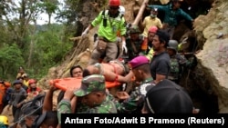 Rescue workers carry a miner who survived the collapse of an illegal gold mine at Bolaang Mongondow regency in North Sulawesi, Indonesia, Feb. 28, 2019.