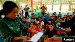 Police give aid to people fleeing from Laukkai, the capital of Kokang in Shan State, who arrived at a monastery functioning as a refugee camp in Lashio, Feb. 16, 2015. 