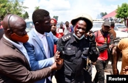 FILE - Ugandan pop star and presidential candidate Bobi Wine,assists one of his bodyguards who was injured in clashes between his supporters and security forces in Kayunga district near Kampala, Uganda, December 1, 2020.