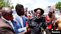 Robert Kyagulanyi akimsaidia mlinzi wake aliyejeruhiwa wakati wa ghasia kati ya wafuasi wake na vikosi vya usalama katika Wilaya ya Kayunga karibu na Kampala, Uganda, Dec. 1, 2020.