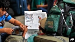 A newspaper shows news about people leaving the city at a railway station in Bangalore, India, Aug. 16, 2012