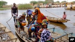 Des femmes peuls traversent un affluent du lac Tchad au village de N'Gouboua, le jeudi 5 Mars, 2015. (AP Photo / Jerome Delay)