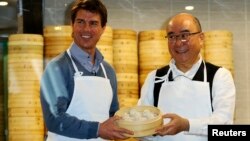 Aktor Tom Cruise berpose bersama Presiden Din Tai Fung Yang Chi-hua dan xiaolongbao, atau dumpling alias pangsit khas restoran tersebut (6/4).