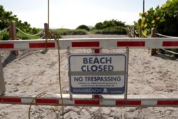 A sign is posted at a closed entrance to the beach during a spike in coronavirus cases, in the South Beach neighborhood of Miami Beach, Florida, July 3, 2020.