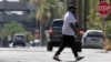 FILE - A pedestrian crosses a street as heat waves rise from the pavement as the temperature hits 104 degrees, June 17, 2024, in Phoenix. Temperature in the city reached 100 degrees for the 100th straight day on Sept. 3, 2024.