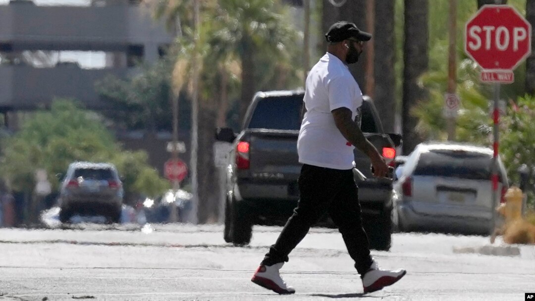 FILE - A pedestrian crosses a street as heat waves rise from the pavement as the temperature hits 104 degrees, June 17, 2024, in Phoenix. Temperature in the city reached 100 degrees for the 100th straight day on Sept. 3, 2024.