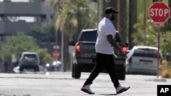 FILE - A pedestrian crosses a street as heat waves rise from the pavement as the temperature hits 104 degrees, June 17, 2024, in Phoenix. Temperature in the city reached 100 degrees for the 100th straight day on Sept. 3, 2024.