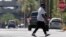 FILE - A pedestrian crosses a street as heat waves rise from the pavement as the temperature hits 104 degrees, June 17, 2024, in Phoenix. Temperature in the city reached 100 degrees for the 100th straight day on Sept. 3, 2024.