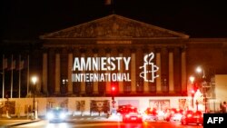 The logo of NGO Amnesty International is projected onto the Palais Bourbon, the seat of the French national assembly, late on June 18, 2018. 