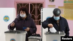 Warga Moldova memasukkan surat suara di sebuah tempat pemungutan suara dalam pemilihan presiden putaran kedua di Chisinau, Moldova, Minggu, 15 November 2020. 