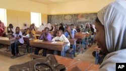 FILE - Schoolchildren listen to a teacher during class in Douentza, Mali. In schools funded by radical Islamists, girls must wear veils and are seated separately in the back or coming at different times altogether.