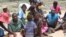 Some women and their children in Mutare West wait for food being cooked in December 2015 under FAO’s Livelihoods and Food Security Program in Zimbabwe.