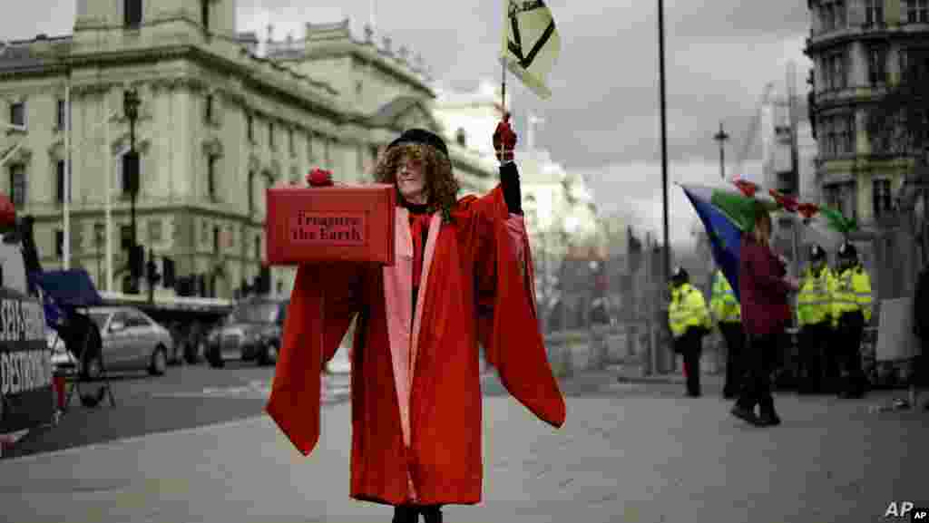 영국 하원의장 복장을 한 여성이 런던 의회 앞에서 예산안 관련 항의 시위를 하는 가운데 &quot;지구를 소중히 여겨라 (Treasure the Earth)&quot;가 적힌 가방을 들고 있다. 