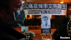 Personas con mascarillas asisten a una vigilia por el médico chino Li Wenliang, quien murió de coronavirus en un hospital de Wuhan el 31 de enero de 2020.