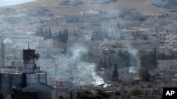 Kepulan asap terlihat membumbung di atas kota Kobani, menyusul pertempuran antara Pasukan Kurdi di Suriah dan militant ISIS dilihat dari puncak bukit di wilayah Suruc, perbatasan Turki-Suriah (21/10).