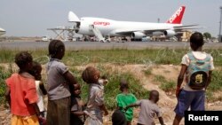 FILE - A humanitarian plane of the World Food Program (WFP) unloads sacks of cereal at Mpoko international airport in Bangui, which is located near a camp for displaced people.