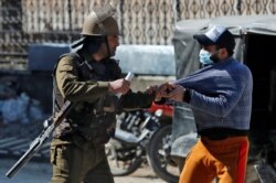 FILE - An Indian police officer detains a demonstrator during a protest after Friday prayers in Srinagar, March 5, 2021.