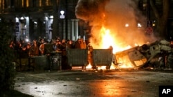 Protesters gather at a barricade with a burning police car, not far from the Georgian parliament building in Tbilisi, Georgia, March 9, 2023.