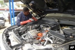 A mechanic from a local car repair shop seen testing the electric system at the front of a customer's car in Addis Ababa, Ethiopia Thursday, Oct. 3, 2024. (AP Photo)