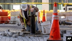 A worker leans on a traffic bollard during demolition of the Black Lives Matter mural in Washington, March 10, 2025.