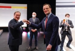 New Christian Democratic Union (CDU) leader Armin Laschet, left, and German Health Minister Jens Spahn bump fists as Deputy CDU Chairman Thomas Strobl watches at the end of the party's 33rd congress, in Berlin, Germany, Jan. 16, 2021.