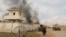 FILE - A member of the Afghan security forces walks as smoke billows from a building after a Taliban attack in Gereshk district of Helmand province, Afghanistan, March 9, 2016.