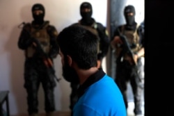 FILE - Kurdish soldiers from anti-terrorism units, background, stand in front a suspected Islamic State member from Turkey at a security center, in Kobani, Syria, July 21, 2017.
