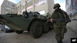 A soldier in an unmarked uniform stands guard at APC outside the Ukrainian Military Prosecutor's Office in Simferopol, Crimea, Mar. 20, 2014.