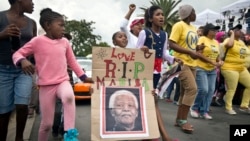 Anak-anak memegang poster Mandela bertuliskan Madiba, nama dimana ia biasa dipanggil di Afrika Selatan, berpawai bersama warga di dekat rumah Mandela di Soweto, Johannesburg 6/12/2013.