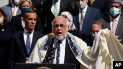 FILE - Rabbi Abraham Cooper, center, of the Simon Wiesenthal Center, speaks in front of civic and faith leaders outside City Hall, Thursday, May 20, 2021, in Los Angeles. 