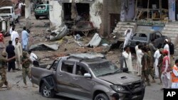 Pakistani security officials and rescue workers examine the site of car bombing on the outskirts of Peshawar, Pakistan, June 2013.