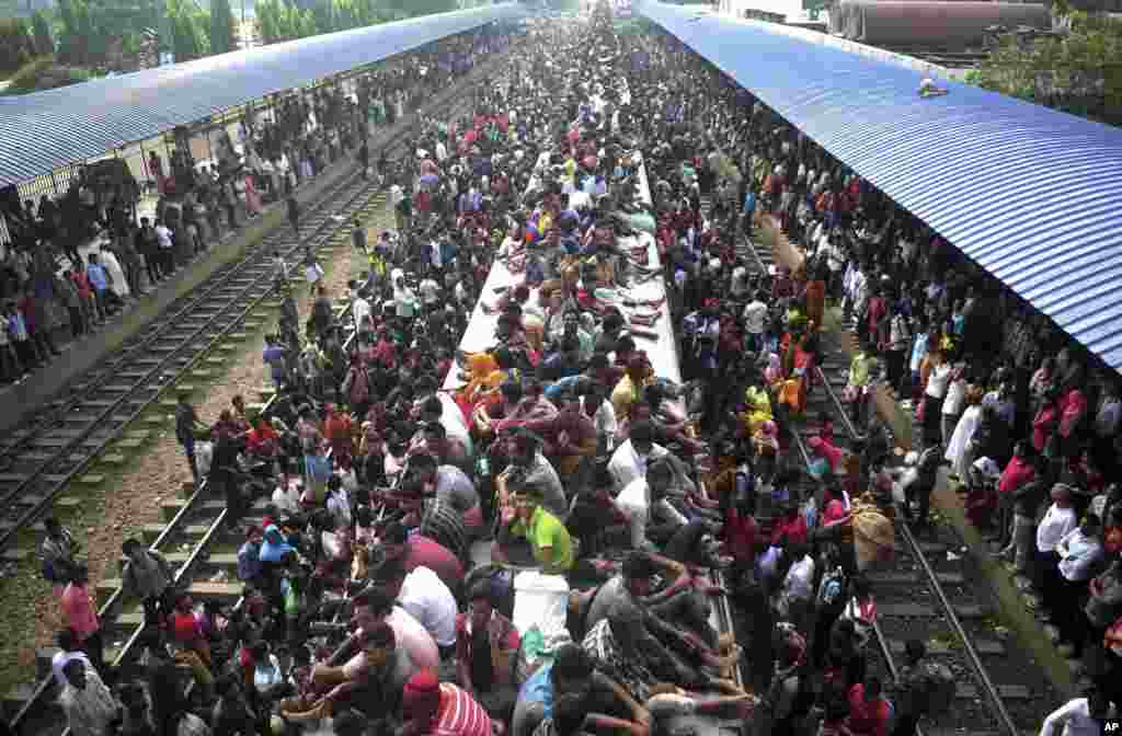 Warga Bangladesh naik di atas atap kereta api saat mereka pulang mudik ke kampung halaman menjelang Idul Adha, di stasiun kereta api di Dhaka, Bangladesh.