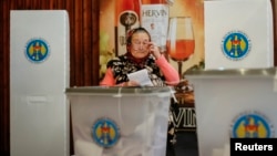 A woman casts a ballot during a parliamentary election at a polling station in Laloveni near Chisinau, Moldova, Nov. 30, 2014. 