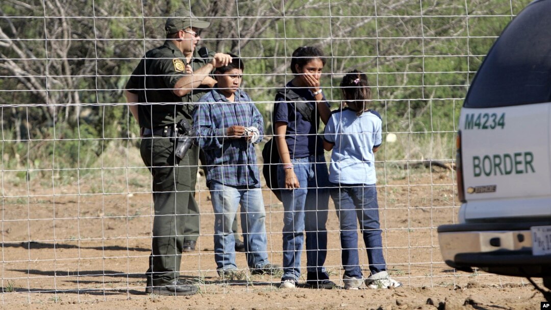 FILE - A Border Patrol agent stands at a ranch fence line with children taken into custody in southern Texas brush country north of Laredo.