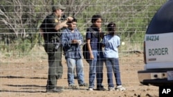 FILE - A Border Patrol agent stands at a ranch fence line with children taken into custody in southern Texas brush country north of Laredo.